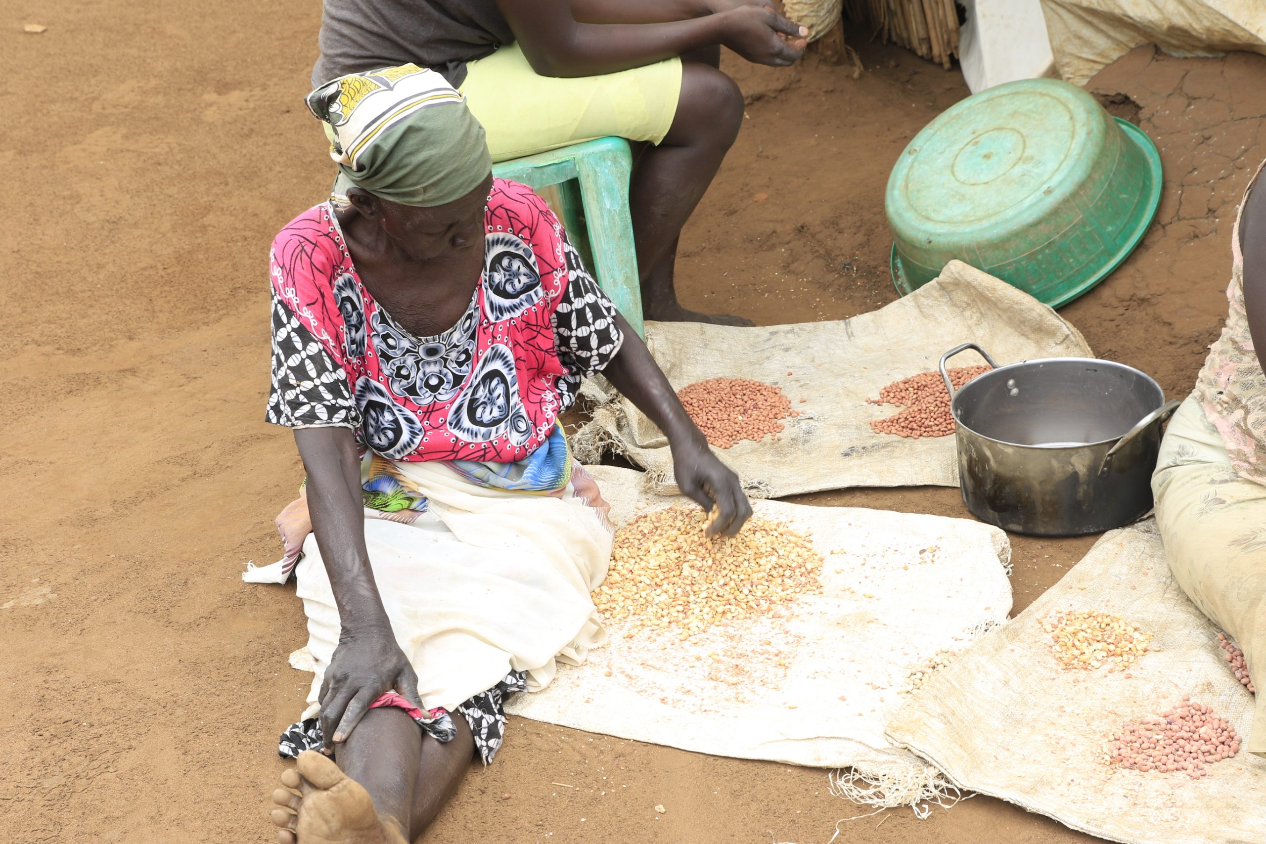 A woman sitting on a mat sorting peanuts